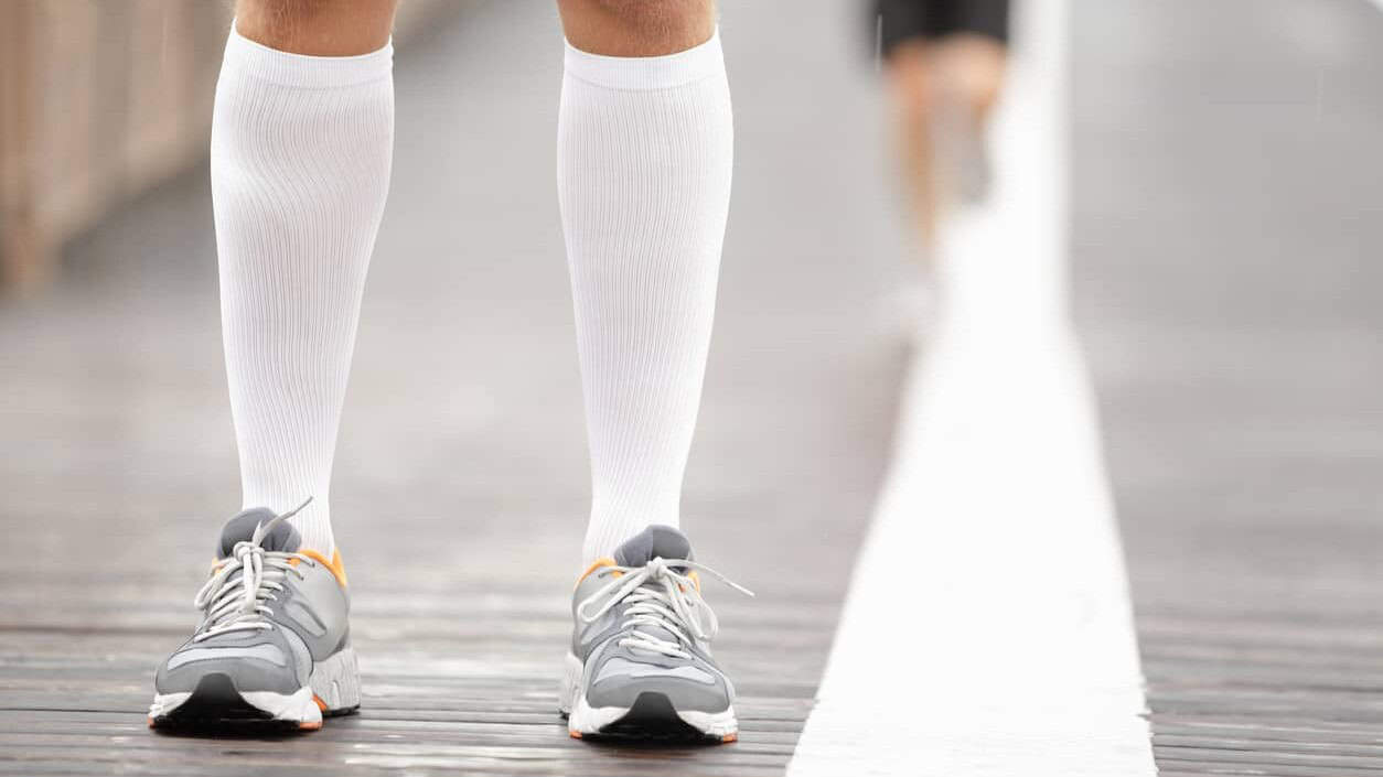 man wearing white compression socks and sneakers