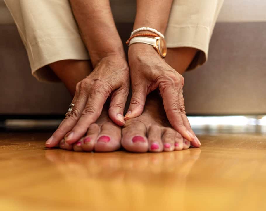 Senior Black woman touches her ankles in pain