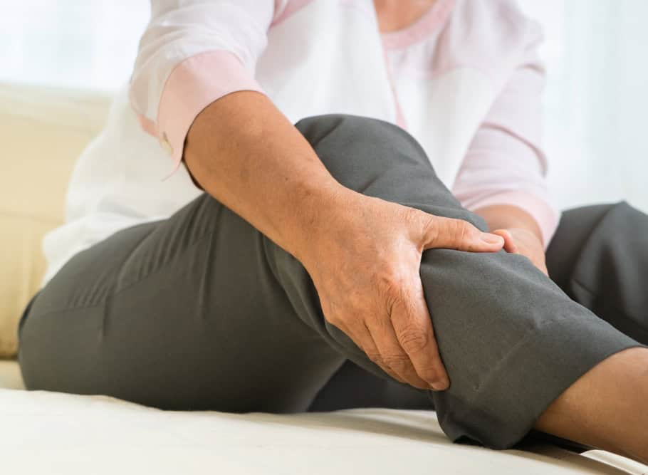 Older woman experiencing heavy, achy legs grabs her calf